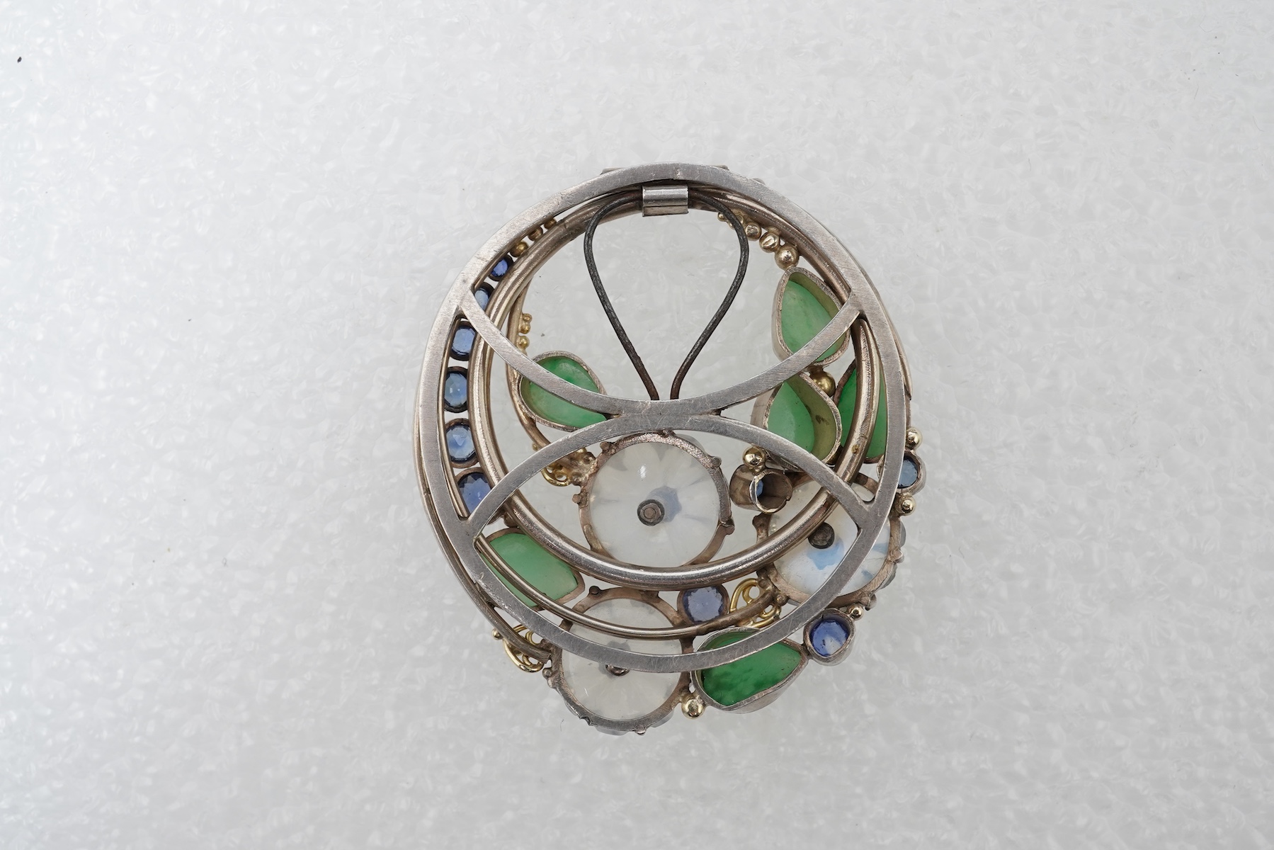 Attributed to Dorrie Nossiter (1893-1977), an Arts & Crafts moonstone, sapphire and jadeite scarf clip, 1920s